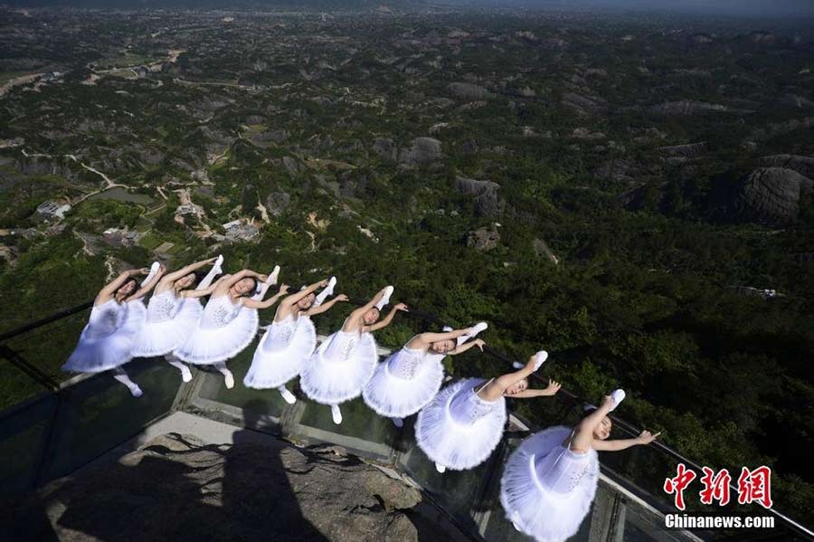 Dancers perform ballet on cliff, glass walkway